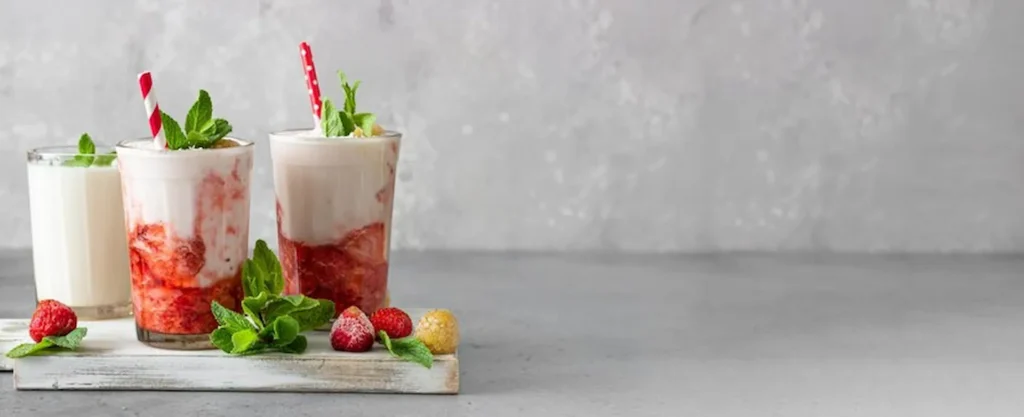 Batidos sustitutivos Herbalife con frutas rojas, servidos en vaso con menta y decoraciones naturales.